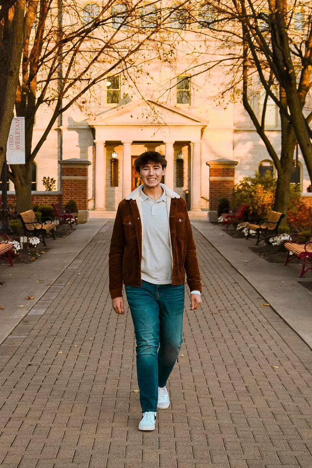 Young man walking on brick campus walkway at golden sunset