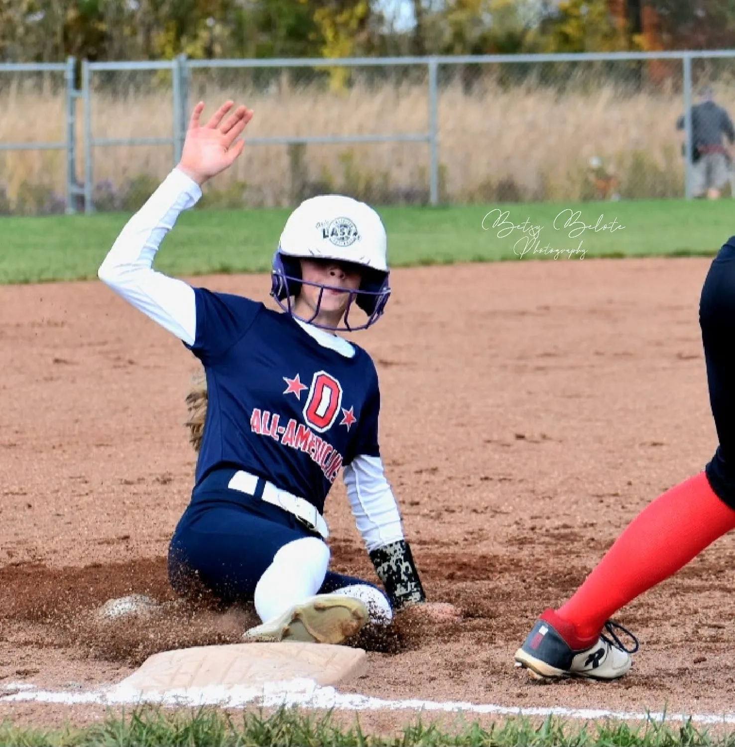 Youth softball player sliding feet-first into base