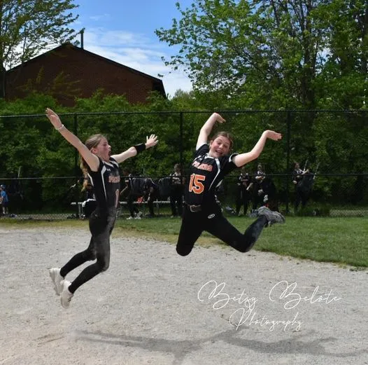 Two Pacers softball teammates leaping in celebratory jump